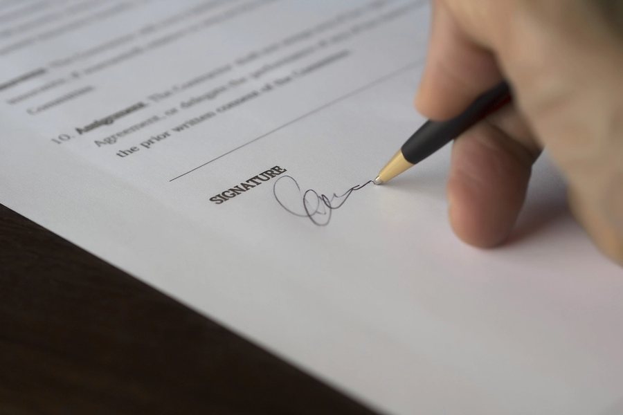 Mano firmando un contrato con un bolígrafo